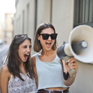 cheerful-young-women-screaming-into-loudspeaker-3764551